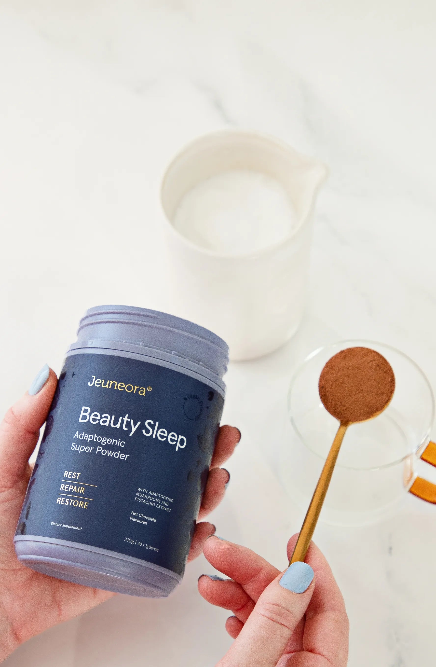 A person holds a container of Beauty Sleep and a scoop of the supplement
