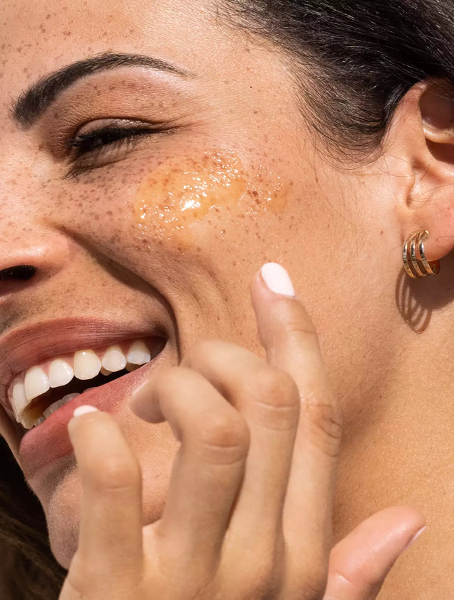 Woman applying vitamin c serum to her glowing face