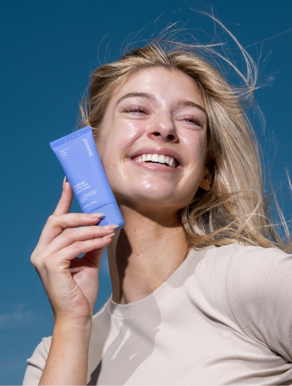 woman posing outside with FullStop.™ SPF50 Daily Glow Screen tube