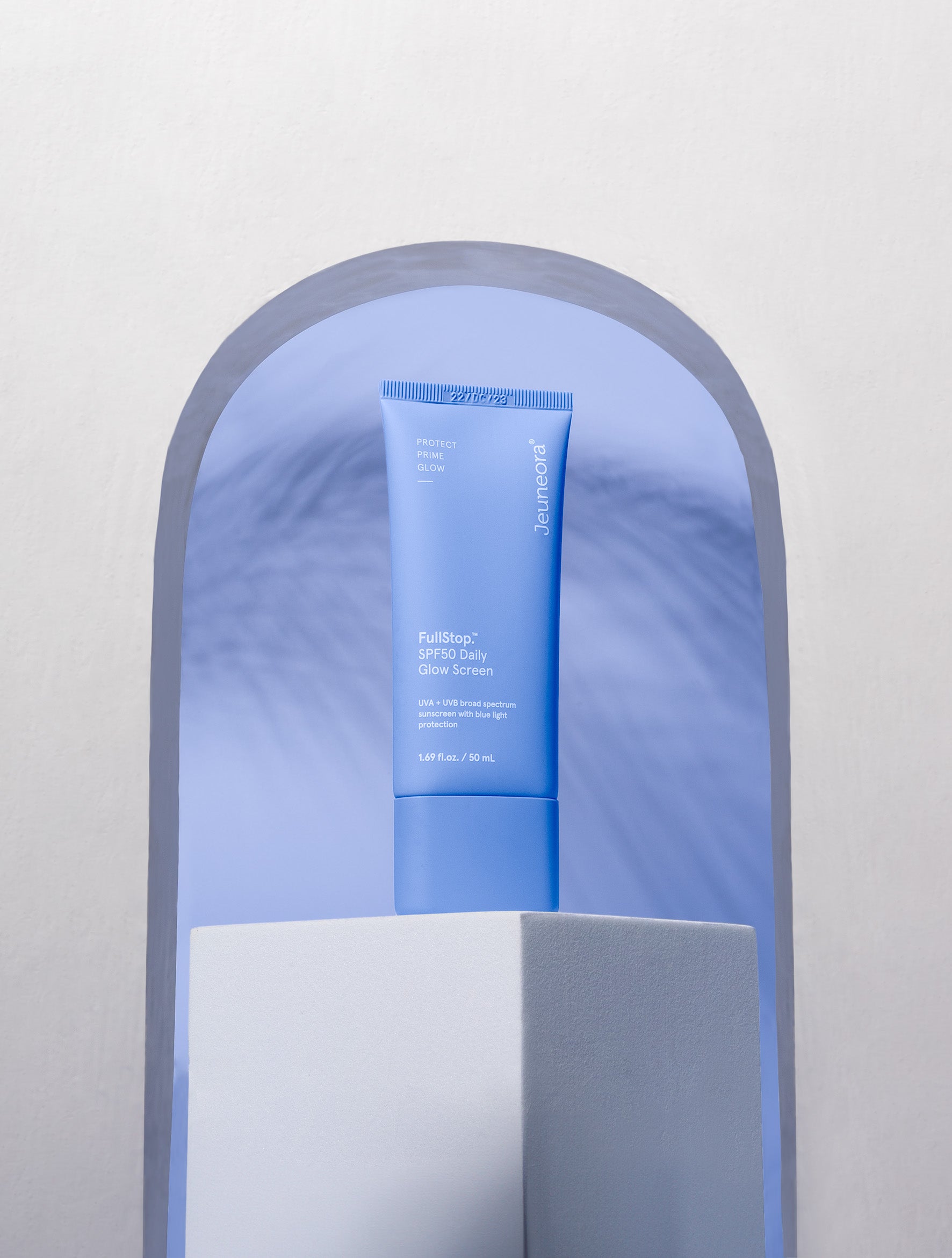 FullStop.™ SPF50 Daily Glow Screen on plinth with blue background