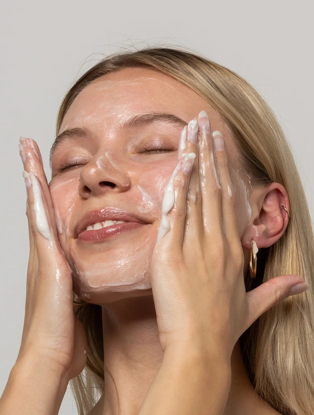 A woman washes her face with OhWhippy 