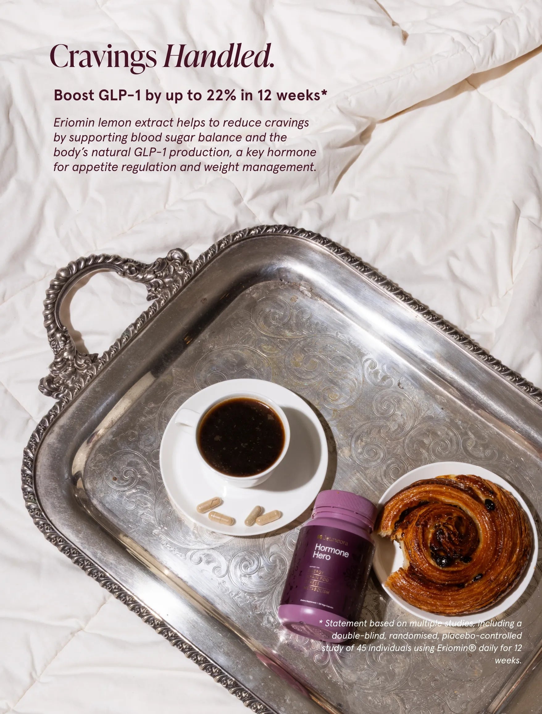 Silver tray with a cup of coffee, cinnamon roll, and Jeuneora Hormone Hero pottle on a white background.